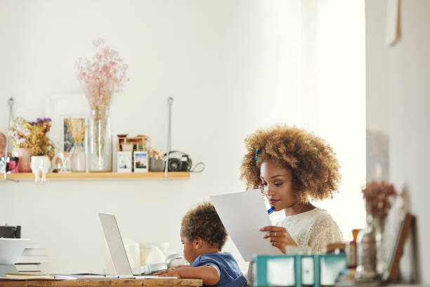 istock Woman reading papers while using laptop with son 1144539407