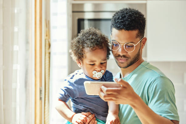 istock Man showing smart phone to son at home 1144539425
