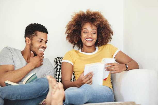 istock Smiling couple talking while reading book at home 1144539824