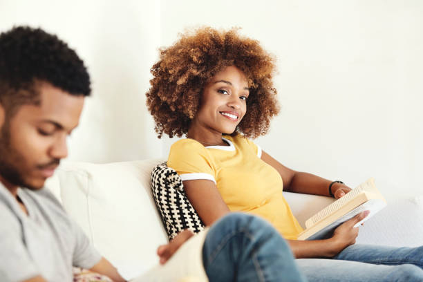 istock Smiling woman reading book while sitting with man 1144539831