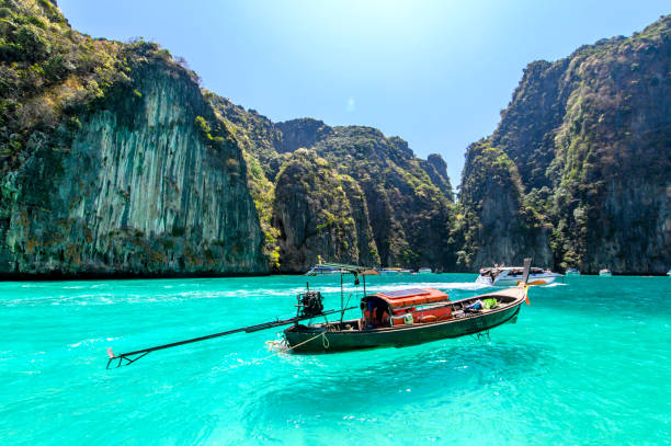 Longtail boats floating on a turquoise and clear sea. Tropical beach with white sand,Phi Phi island,Thailand. Longtail boats floating on a turquoise and clear sea. Tropical beach with white sand,Phi Phi island,Thailand. phi phi islands stock pictures, royalty-free photos & images