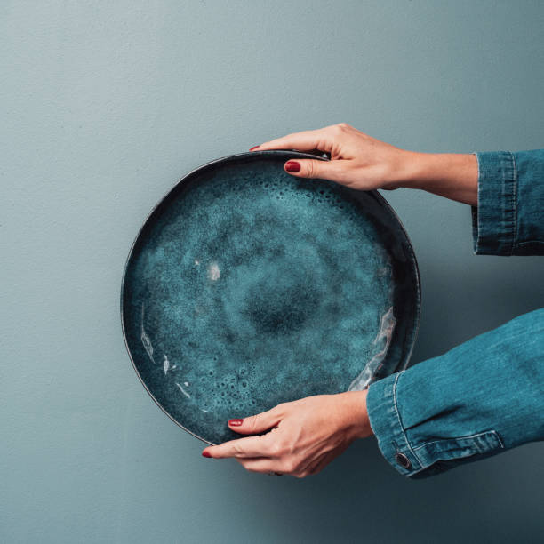 istock Woman holding beautiful platter plate against blue 1144545664