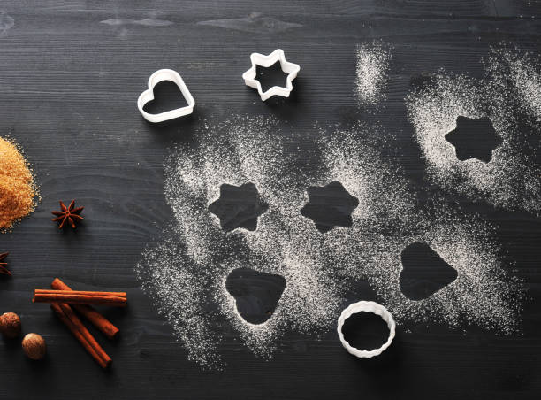 istock The dark wooden surface is sprinkled with flour. In the frame, several forms for biscuits, cane sugar, cinnamon sticks, nutmeg and anise. 1144546578