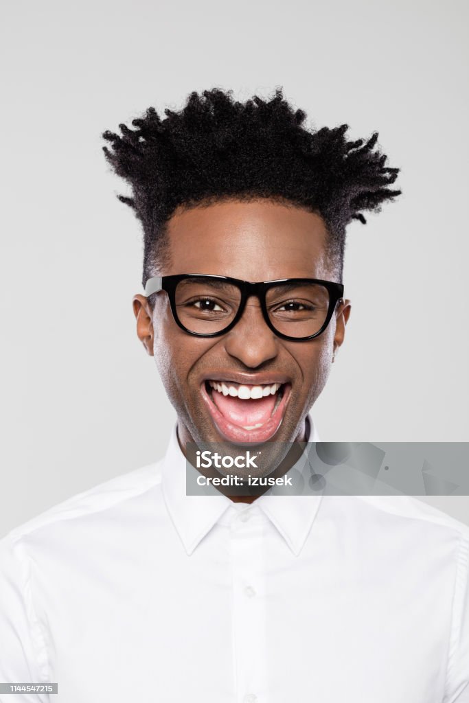 Excited afro american young businessman Close up portrait of excited afro american young businessman on gray background. Man in white shirt wearing eyeglasses with funky hairstyle. Men Stock Photo