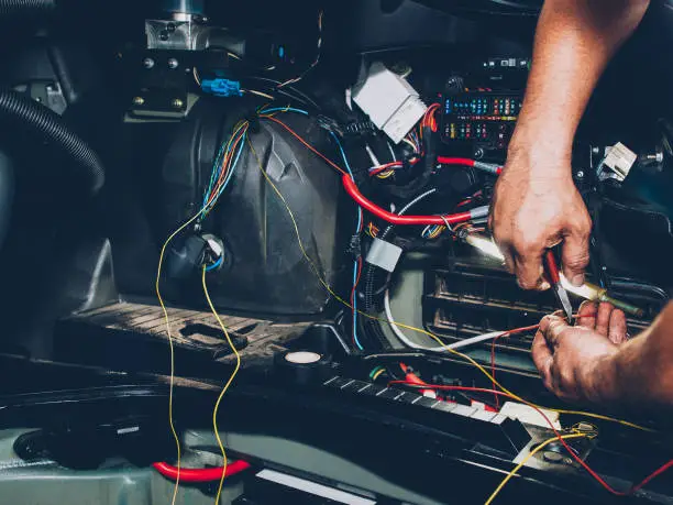 Mechanic electrician checking repairing upgrading wiring. Auto service workshop. Regular preventive car maintenance.