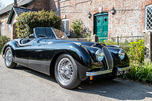 Moreton, UK - 20 April 2019: Pristine vintage black Jaguar sports car parked in the village of Moreton, Dorset, UK