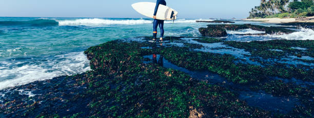 istock Woman surfer with surfboard going to surf 1144548905