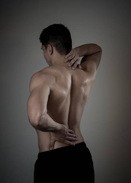 Young muscular fitness man touching and grabbing his neck and lower back suffering cervical pain isolated on neutral background. In sport and workout injury, Incorrect posture problems and body care. joven hombre fitness musculoso tocando y agarrando su cuello y la parte inferior de la espalda sufriendo dolor cervical aislado en el fondo neutro. en el deporte y la lesión del entrenamiento, problemas de postura incorrectos y cuidado del cuerpo.