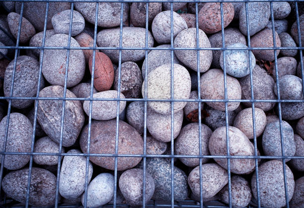 istock Rock stones behind metal grid fence texture background hd 1144552329