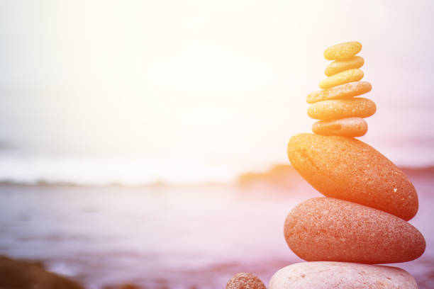 баланс, релаксация и благополучие: каменный кайрн снаружи, океан на размытом фоне - tranquil scene stone massaging zen like стоковые фото и изображения