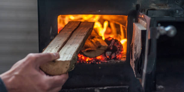 istock Man putting log to wood burning stove 1144553520