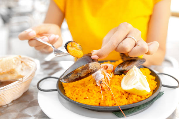 young woman eating spanish paella in outdoor restaurant