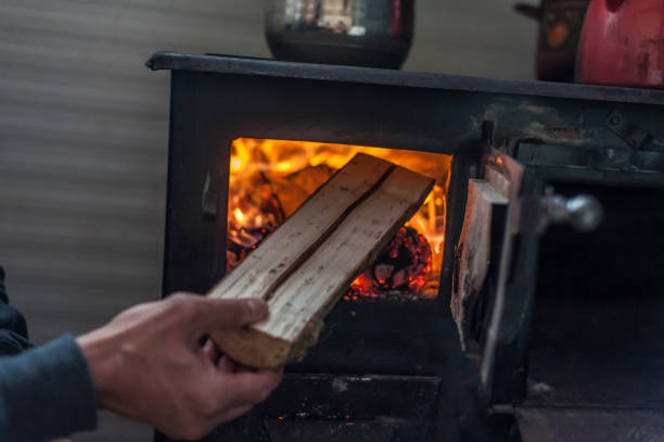 istock Man putting log to wood burning stove 1144554232