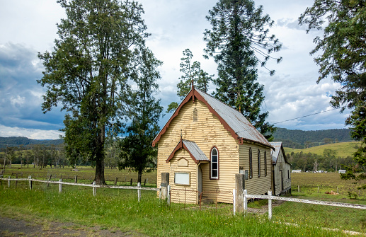 Salisbury, Australia - Dec 29, 2017: A small derelict country church made of weathered wooden panels sits within a grazing paddock. Image captured from a fast moving vehicle.