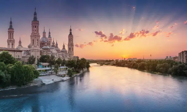 Basilica Cathedral of Our Lady of Pillar and bridge over Ebro River at sunset in Zaragoza, Aragon, Spain. Famous tourist landmark