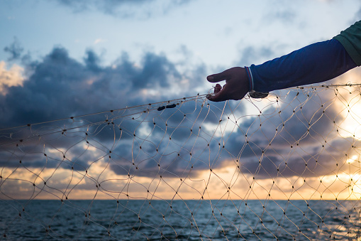 Fisherman hand and net working on the sunset.