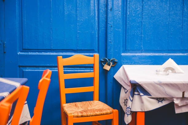 Orange wooden chairs against blue doors, Greece
