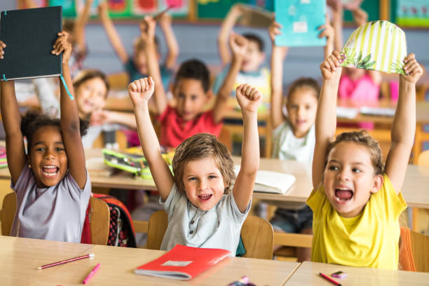 Elementary school kids raising their hands to answer a question.