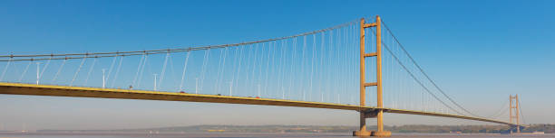 Web banner style image of the Humber Bridge that joins Hessle in Yorkshire to Barton in Lincolnshire. Web banner style view of the Humber Bridge on the south bank of the River Humber.  The bridge joins Hessle in Yorkshire to Barton in Lincolnshire.  It was once the longest single span suspension bridge in the world. humberside stock pictures, royalty-free photos & images