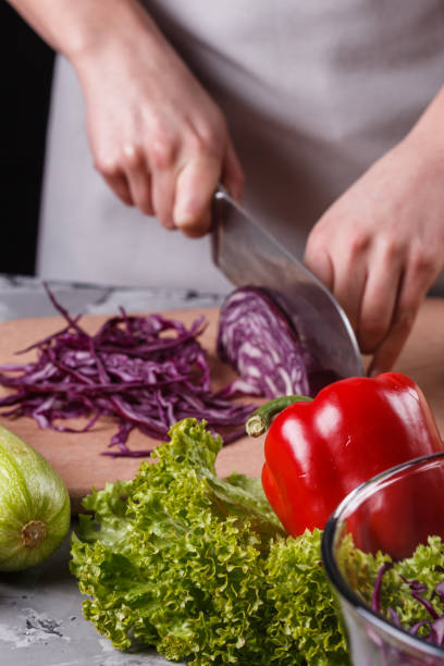 istock a young woman in a gray apron cuts red cabbage 1144566131