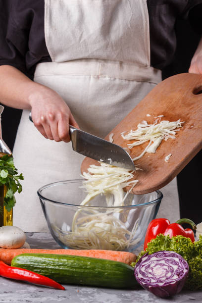 istock young woman in a gray apron cut cabbage 1144566479
