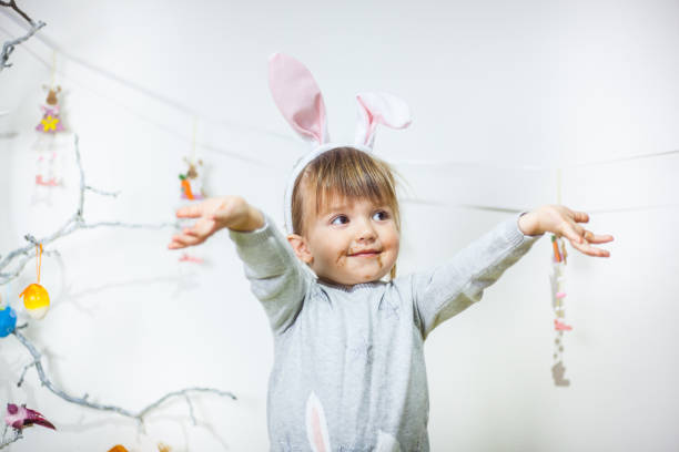 douce petite fille sale avec le chocolat portant des oreilles de lapin et jouant la chasse aux oeufs sur pâques - figurine easter egg easter holiday photos et images de collection