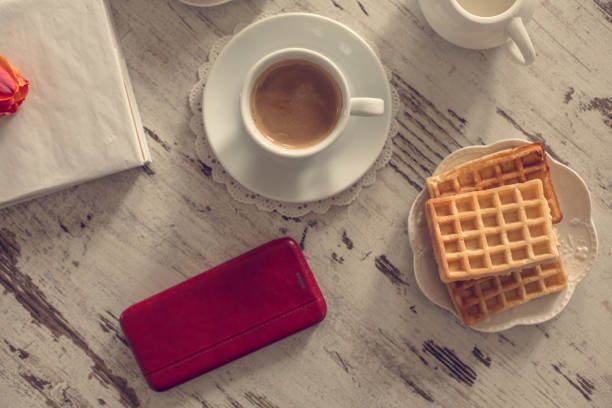Coffee, waffles, smart phone and book on the table