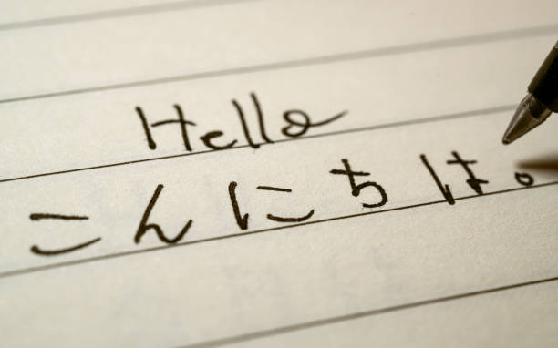aprendiz de principiante del idioma japonés escribiendo hello word en caracteres japoneses de hiragana en una foto de cerca de un cuaderno - escritura japonesa fotografías e imágenes de stock