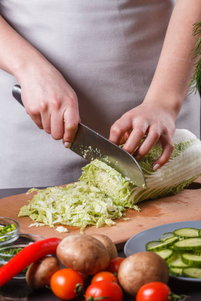 istock A young woman in a gray apron cuts chinese cabbage 1144570766