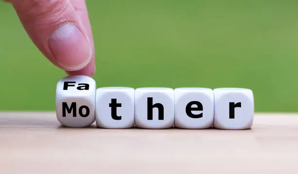Father or Mother? Hand turns a dice and changes the word "Mother" to "Father" (or vice versa). Concept for child custody.
