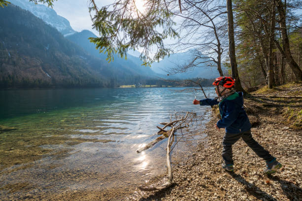 5-letni chłopiec rzuca kamieniami w krystalicznie czystą wodę vorderer langbathsee w pobliżu ebensee, oberösterreich, austria - throwing stone little boys child zdjęcia i obrazy z banku zdjęć