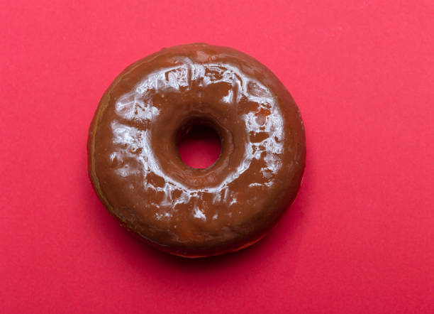 Chocolate donut isolated on red color background, top close up view