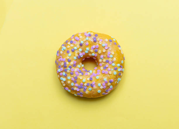istock Doughnut with star shape sprinkles isolated on yellow color background 1144573913