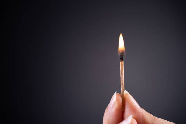 istock Close up woman hand holding a burning match. 1144574078