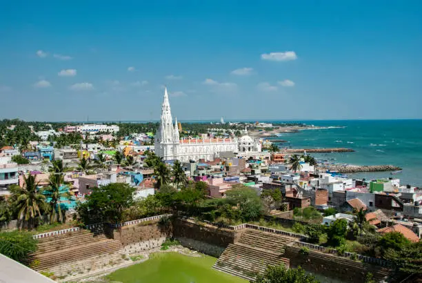 Our Lady of Ransom Shrine Church behind colorful houses on a sand beach occupied by fishing boats in Kanyakumari in India