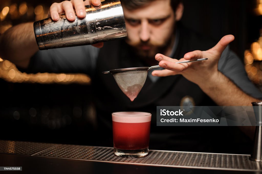 Baarimikko kaataa sileän vaaleanpunaisen cocktailin seulan läpi lasiin - Rojaltivapaa avainsanalla Baarimestari ja tyyppiä Kuvapankin valokuva Baarimikko kaataa sileän vaaleanpunaisen cocktailin seulan läpi lasiin - Rojaltivapaa avainsanalla Baarimestari ja tyyppiä Kuvapankin valokuva