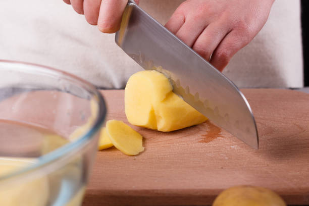 istock young woman in an apron cuts potatoes 1144575901