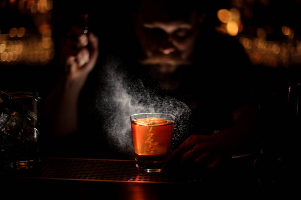 istock Bartender spraying to the cocktail glass with one big ice cube in the dark 1144576355