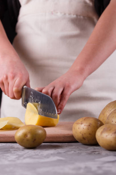 istock young woman in an apron cuts potatoes 1144578755