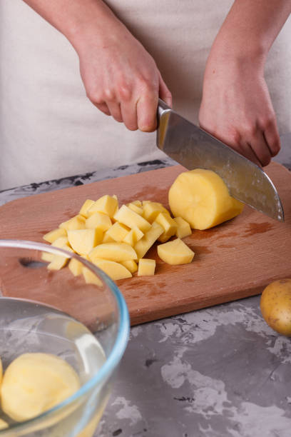 istock young woman in an apron cuts potatoes 1144578769
