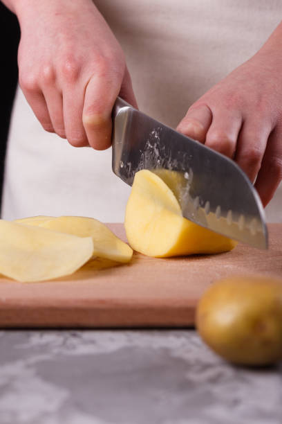 istock young woman in an apron cuts potatoes 1144578799