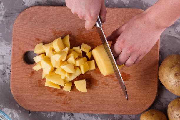 istock young woman in an apron cuts potatoes 1144578867