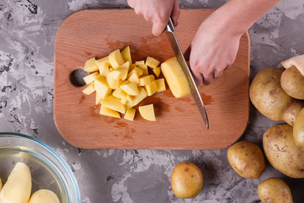 istock young woman in an apron cuts potatoes 1144578943
