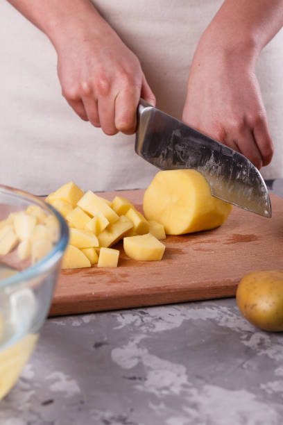 istock young woman in an apron cuts potatoes 1144578964