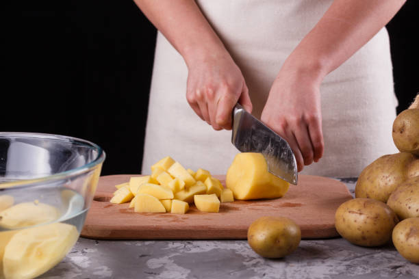 istock young woman in an apron cuts potatoes 1144578988