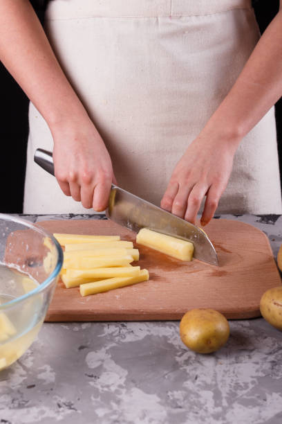 istock young woman in an apron cuts potatoes 1144579404