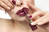 Multi-colored nail design.Trendy Burgundy nail Polish and lip makeup.