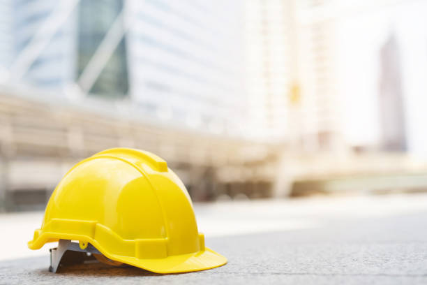 yellow hard safety wear helmet hat in the project at construction site building on concrete floor on city with sunlight. helmet for workman as engineer or worker. concept safety first. stock photo