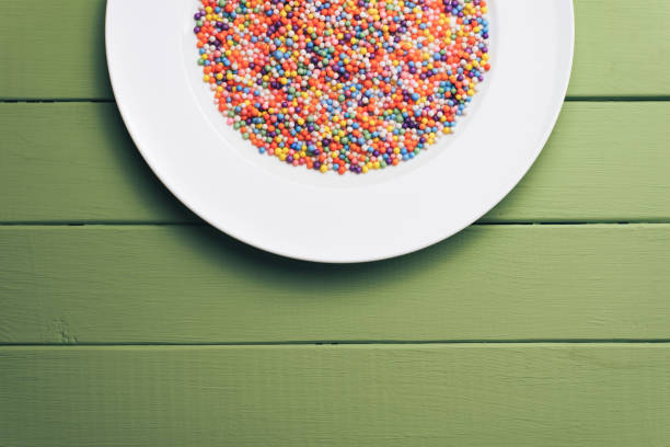 istock White plate with color preparations (vitamins, dyes, flavor enhancers, nutritional supplements, innovative technologies, candy sweets) on an green wooden table background. 1144581143