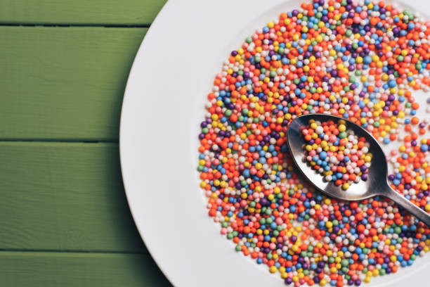 istock White plate with color preparations (vitamins, dyes, flavor enhancers, nutritional supplements, innovative technologies, candy sweets) on an green wooden table background. 1144581247